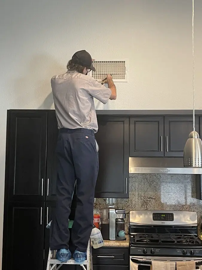 Technician inspecting an air vent during HVAC service in Crestview